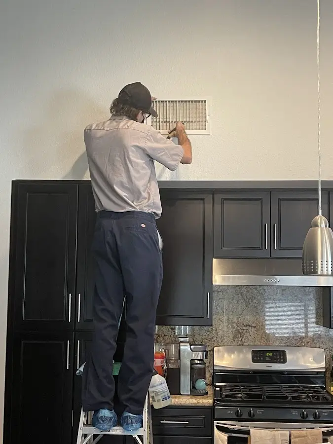 Technician inspecting an air vent during HVAC service in Chamblee